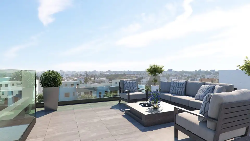 Roof terrace with grey outdoor sofas, coffee table and planters above the Larnaca skyline