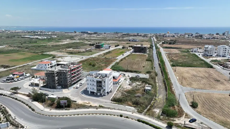 Aerial photograph of the buildings beside a roundabout with open fields and coastline behind